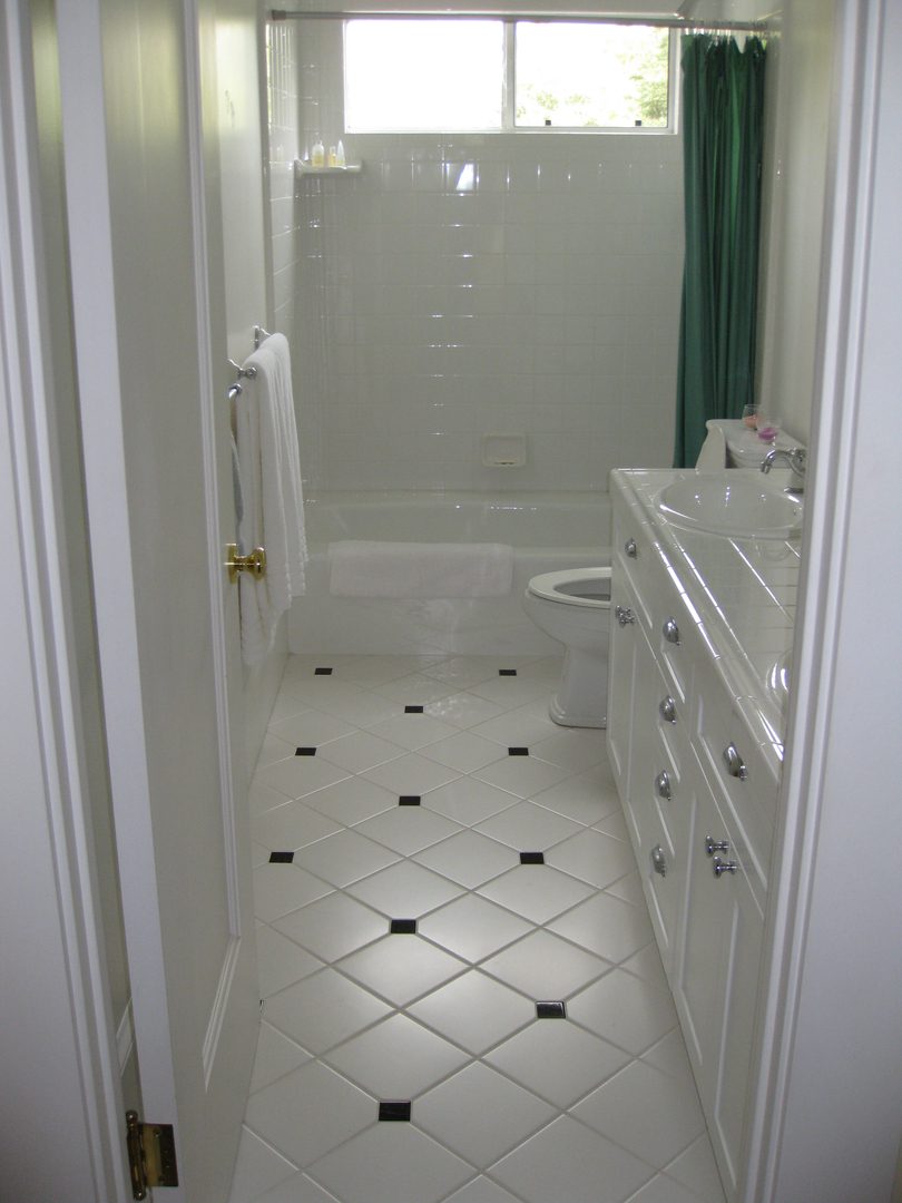 White tiled bathroom with green shower curtain.