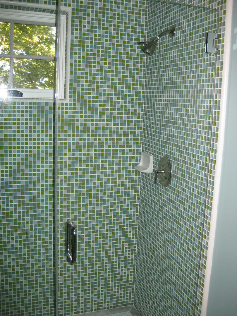 Modern shower with small green tiles.