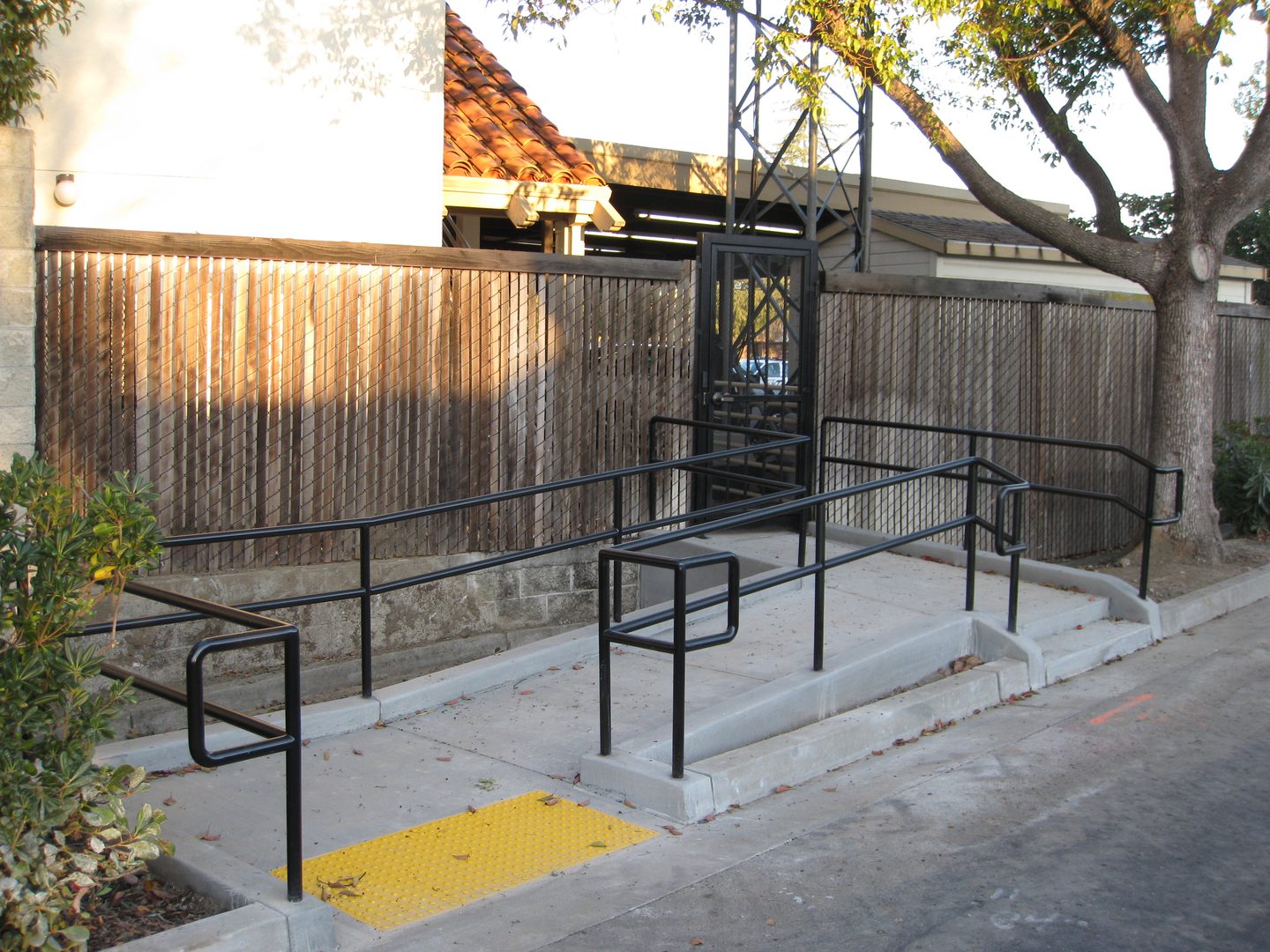 Outdoor accessibility ramp beside wooden fence